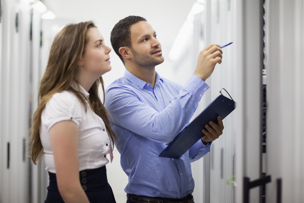 Technicians with clipbard looking at servers in data center